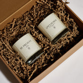 Boujie On Vacation and For Peace candle boxes arranged with branded cardboard packaging.